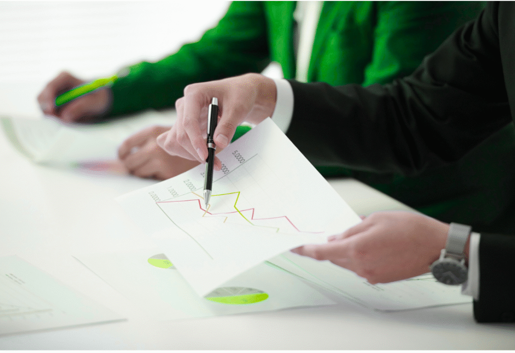 Personen besprechen ein Dokument mit Diagrammen und Datenanalysen.